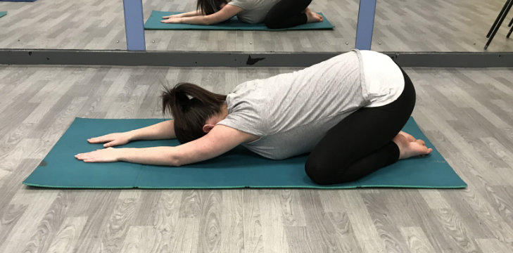 A person in a low yoga pose facing the floor